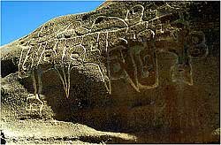 The words Hom Mani Padme Hom are inscribed in a large carving on the rock wall
